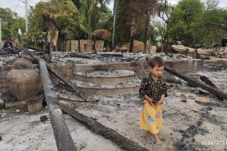 Child in front of burned down home